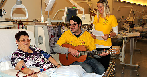 2 Schüler mit Gitarre am Bett einer Dialysepatientin