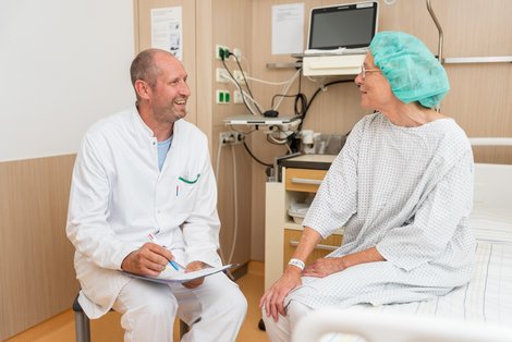 Arzt gleich Patientinnendaten mit Patientin ab, die am Bett sitzt