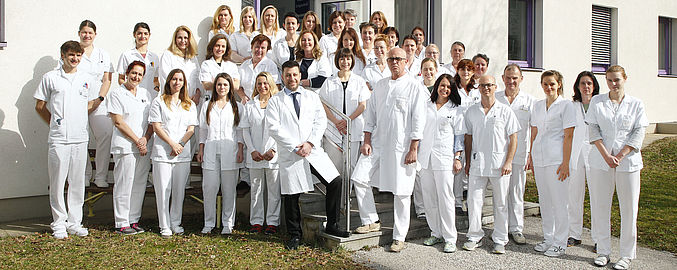Team der Pathologie Pyhrn-Eisenwurzen Klinikum Steyr. Gesamtes Team steht vor dem PathologieZentrum im Garten. Haben weiße Berufskleidung an. Grüne Wiese. Stöckelplaster.