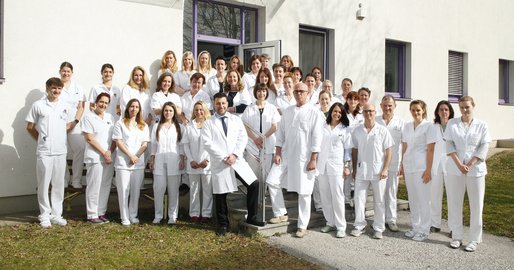 Team der Pathologie Pyhrn-Eisenwurzen Klinikum Steyr. Gesamtes Team steht vor dem PathologieZentrum im Garten. Haben weiße Berufskleidung an. Grüne Wiese. Stöckelplaster.