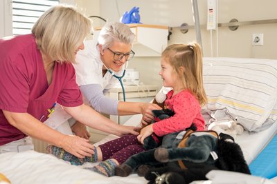 Kinderärztin und Krankenpflegerin kümmern sich um Kind im Krankenbett