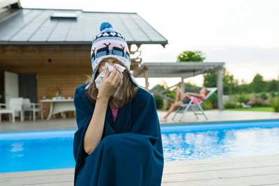 Person mit Taschentuch und Haube vor Schwimmbad