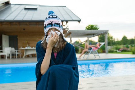 Person mit Taschentuch und Haube vor Schwimmbad