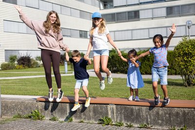Fünf Kinder springen von niedriger Mauer