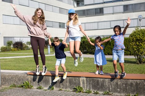 Fünf Kinder springen von niedriger Mauer