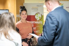 Eine Frau eines Selbsthilfestandes unterhält sich im Klinikum Schärding mit BesucherInnen