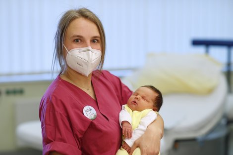 Hebamme mit Baby in den Händen