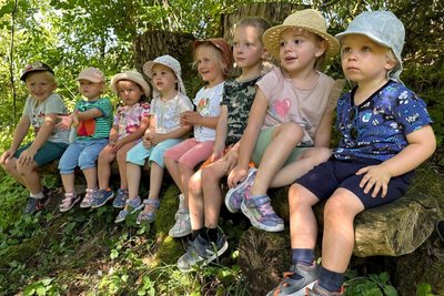 Kleinkinder sitzen auf Baumstamm im Wald