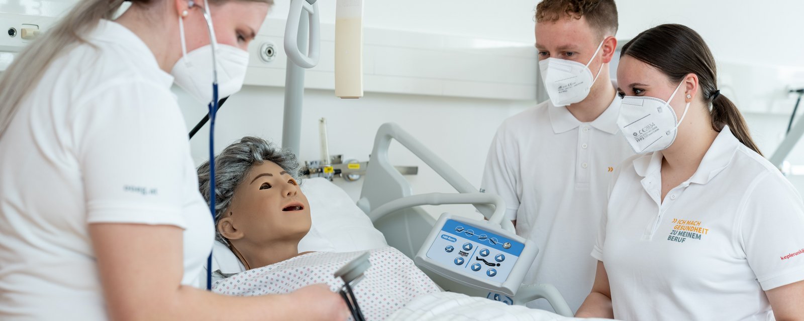 Schülerinnen beim Blutdruckmessen an Simulationspuppe