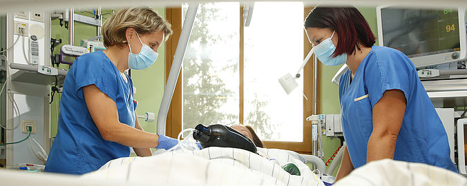 Zwei Mitarbeiterinnen an einem Krankenbett auf der Intensivstation