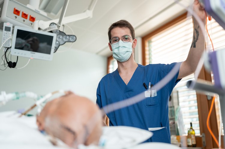 Pfleger an einem Intensivbett mit beatmetem Patienten