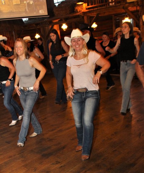 Sylvia Hollnsteiner im Vordergrund beim Line Dance mit anderen TänzerInnen im Countryoutfit
