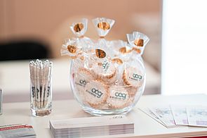Kugelschreiber und Kekse in Gläsern und Broschüren auf einem Tisch
