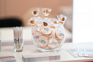 Kugelschreiber und Kekse in Gläsern und Broschüren auf einem Tisch