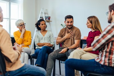 Menschen sitzen in Sesselkreis und reden