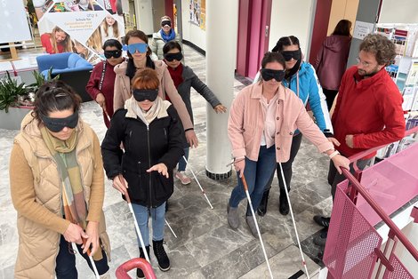 Auszubildende mit Blindenstock und Augenbinde beim hinabgehen einer Stiege