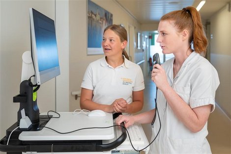 Ausbildnerin und Schülerin stehen vor Visitenwagen mit Bildschirm