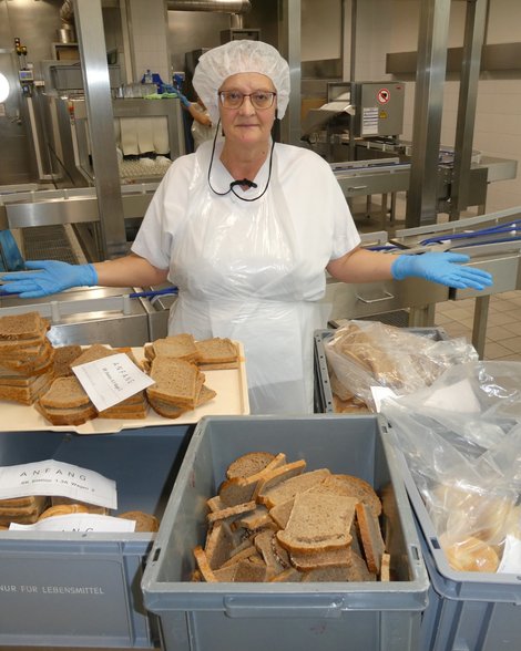 Köchin steht im Pyhrn-Eisenwurzen Klinikum vor Kisten mit Brotscheiben
