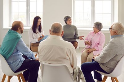 ältere Personen sitzen im Kreis und reden miteinander