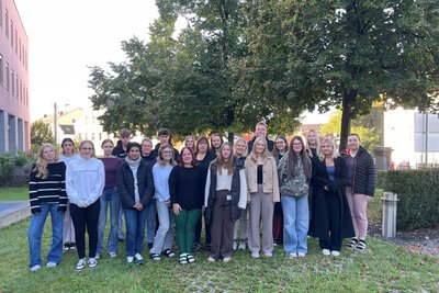 Gruppenfoto der Auszubildenden in einer Wiese mit Baum im Hintergrund