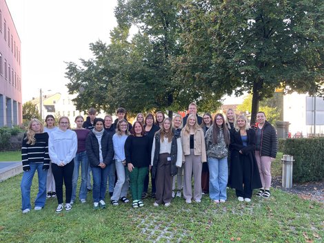 Gruppenfoto der Auszubildenden in einer Wiese mit Baum im Hintergrund
