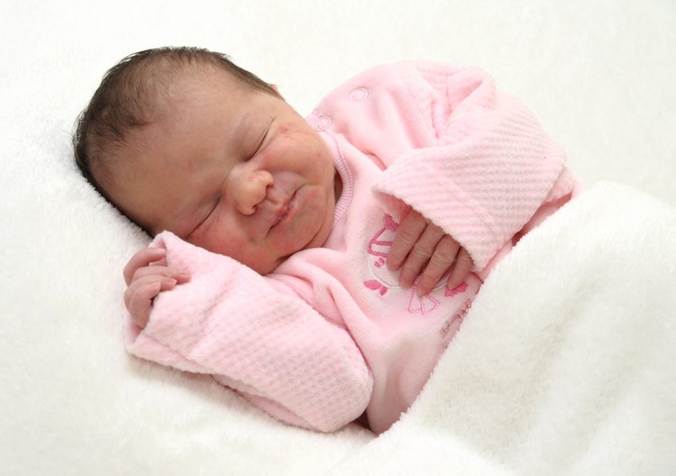 Baby in rosa Jacke mit weißer Decke