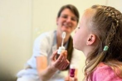 Mädchen sitzt am Schoss der Mama und bläst Seifenblasen