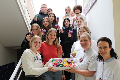 Gruppenbild auf Stiege mit Korb voll Filz-Schmetterlingen in der Hand