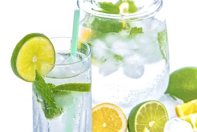 Glas und Krug mit Wasser, Eiswürfel und Limettenscheiben
