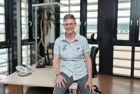 Portraitbild von Ruth Bahmann, im Hintergrund ihr Büro