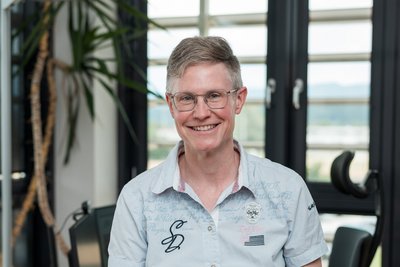 Portraitbild von Ruth Bahmann, im Hintergrund ihr Büro