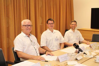 Drei Ärzte sitzen an einem Tisch - Pressekonferenzsituation