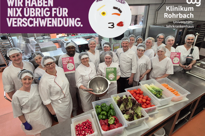 Gruppenbild Küchenteam mit Lebensmitteln und dem Schriftzug "Wir haben nix übrig für Verschwendung"