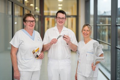 Arzt, Pflegekraft und Physiotherapeutin mit Gelenksprothesen