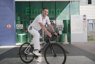 Daniel Hochstraßer auf seinem Fahrrad vor dem Eingang des Salzkammergut Klinikum Vöcklabruck