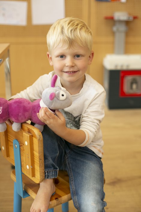Kind mit Kuscheltier Raupi