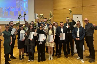 Gruppenfoto AbsolventInnen mit Rosen und Abschlusszeugnis