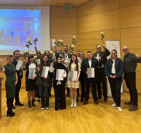 Gruppenfoto AbsolventInnen mit Rosen und Abschlusszeugnis