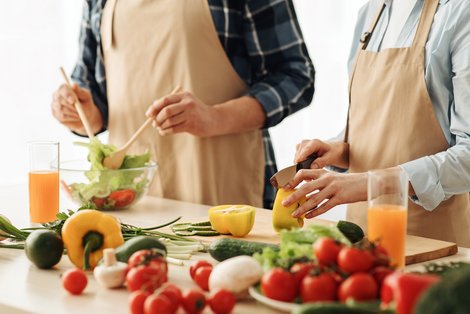 Zwei Personen schneiden Gemüse und Obst an einem Tisch