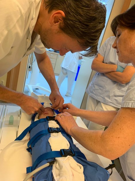 Arzt und Kollegin packen Säugling in Vakuummatratze