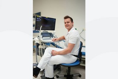 Arzt sitzt vor Untersuchungsgerät