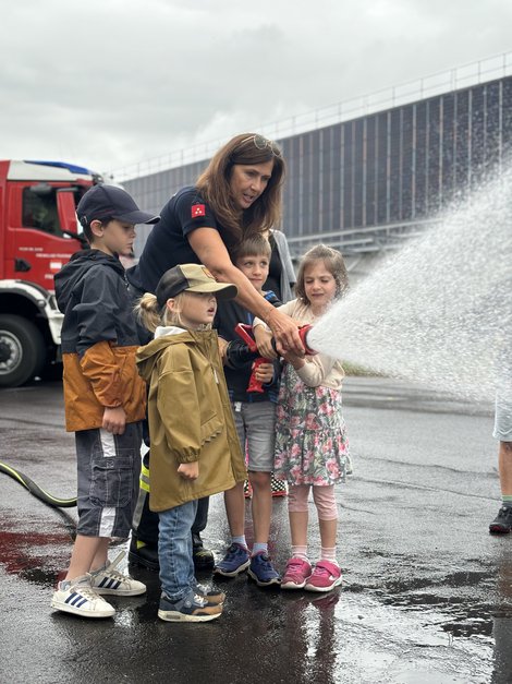 Kinder spritzen mit Feuerwehrschlauch