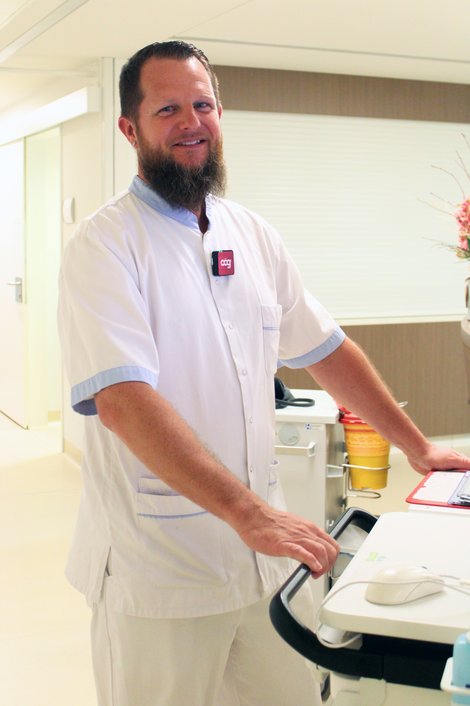 DGKP Michael Kerschhofer steht an einem mobilen Visitenwagen auf der Station für Unfallchirurgie und Orthopädie.