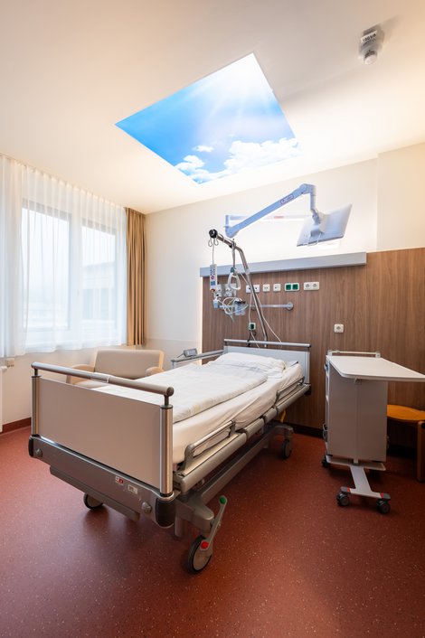 Krankenhausbett mit Wolkenbild an der Decke