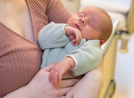 Baby wird im Arm gehalten