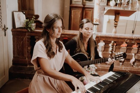 Eva-Maria und ihre Schwester Claudia spielen mit Klavier und Gitarre in einer Kirche