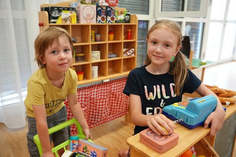 Kinder spielen während der Sommerkinderbetreuung im Salzkammergut Klinikum Bad Ischl in einer nachgestellten Einkaufssituation mit Spielkassa und Einkaufswagen.