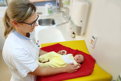 Krankenpflegerin kümmert sich um Neugeborenes 