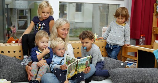 Kinderbetreuerin liest ein Buch vor.