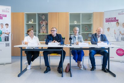 Pressekonferenz-Situation, Teilnehmer sitzen an Tischen